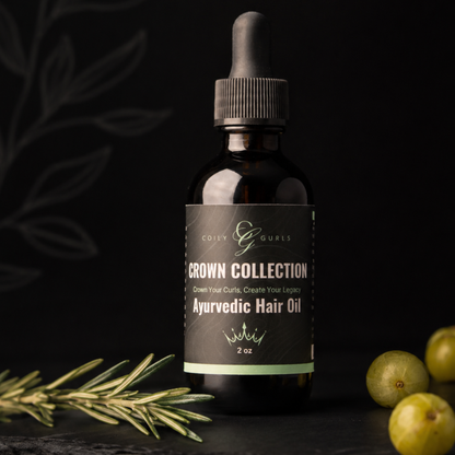 Bottle of Crown Collection Ayurvedic Hair Oil with a dark background and green leaves and fruits.